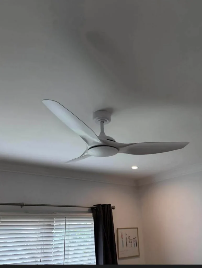 Modern three-blade white ceiling fan installed flush to the ceiling in a tidy bedroom