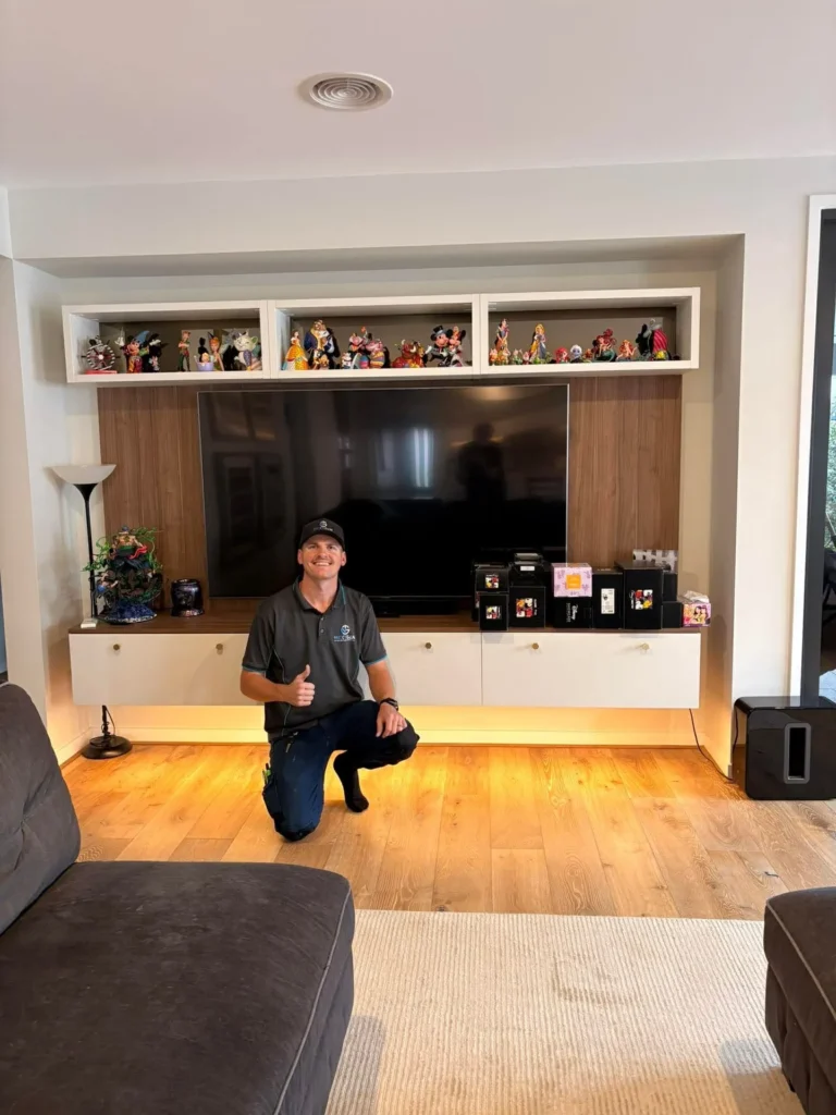 Harley from NextGen Electricians giving a thumbs up in front of a newly wall-mounted TV and entertainment unit