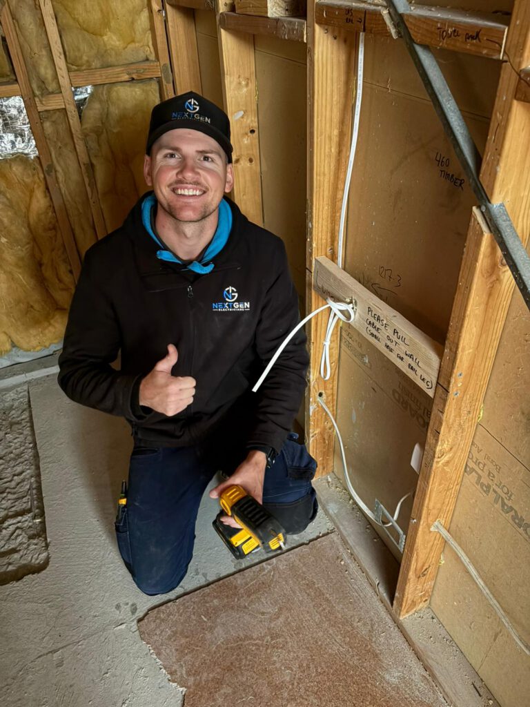 Harley kneeling inside a renovation at rough-in stage, new cable runs visible through open timber framing