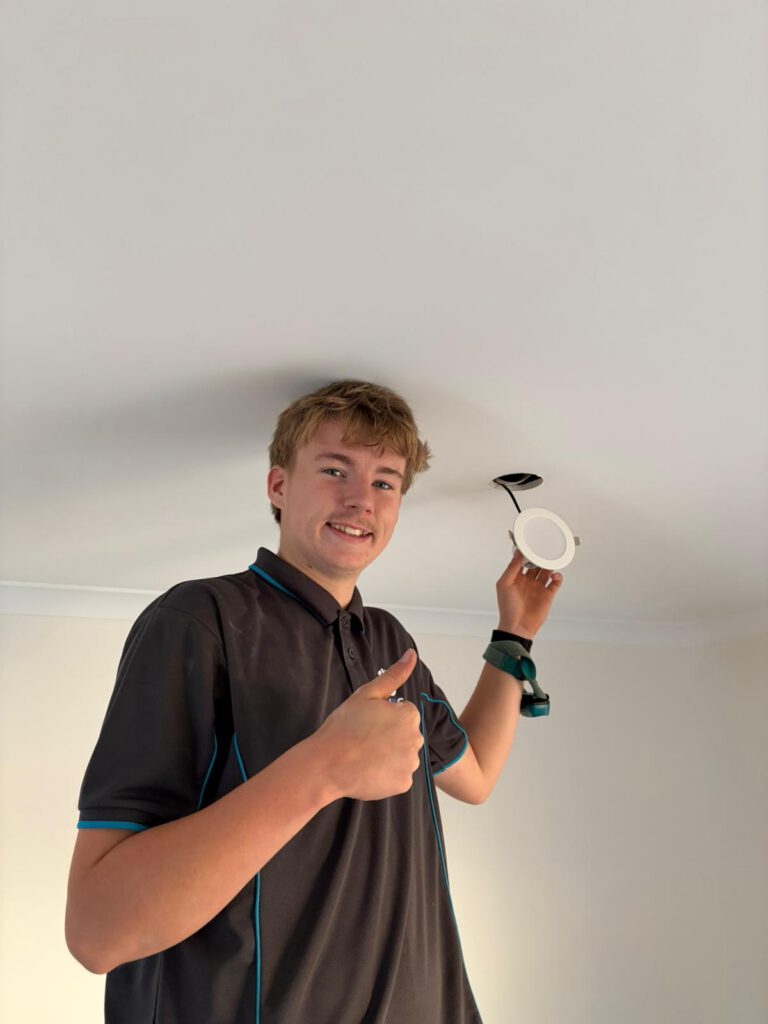 Jakob holding an LED downlight before fitting it into the ceiling during a whole-house downlight upgrade