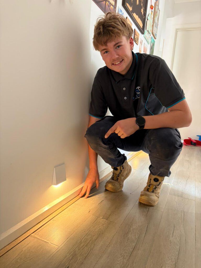 Jakob pointing to a low-level LED skirting wall light installed in a hallway, part of a lighting feature upgrade