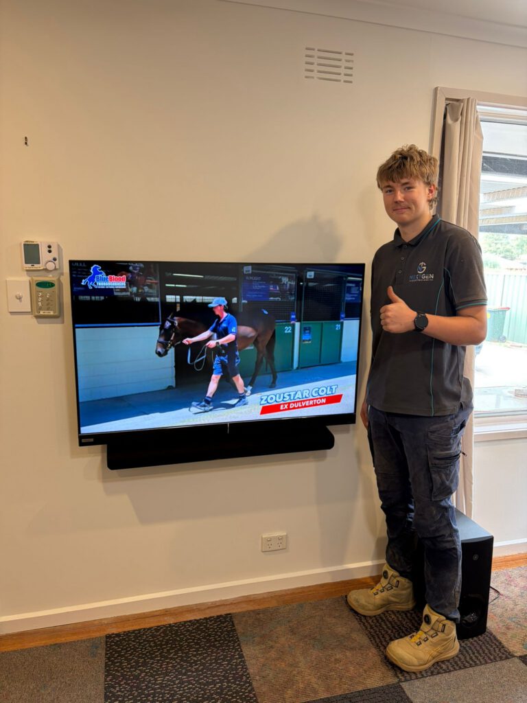 Jakob next to a wall-mounted TV and soundbar he installed in a Bacchus Marsh living room