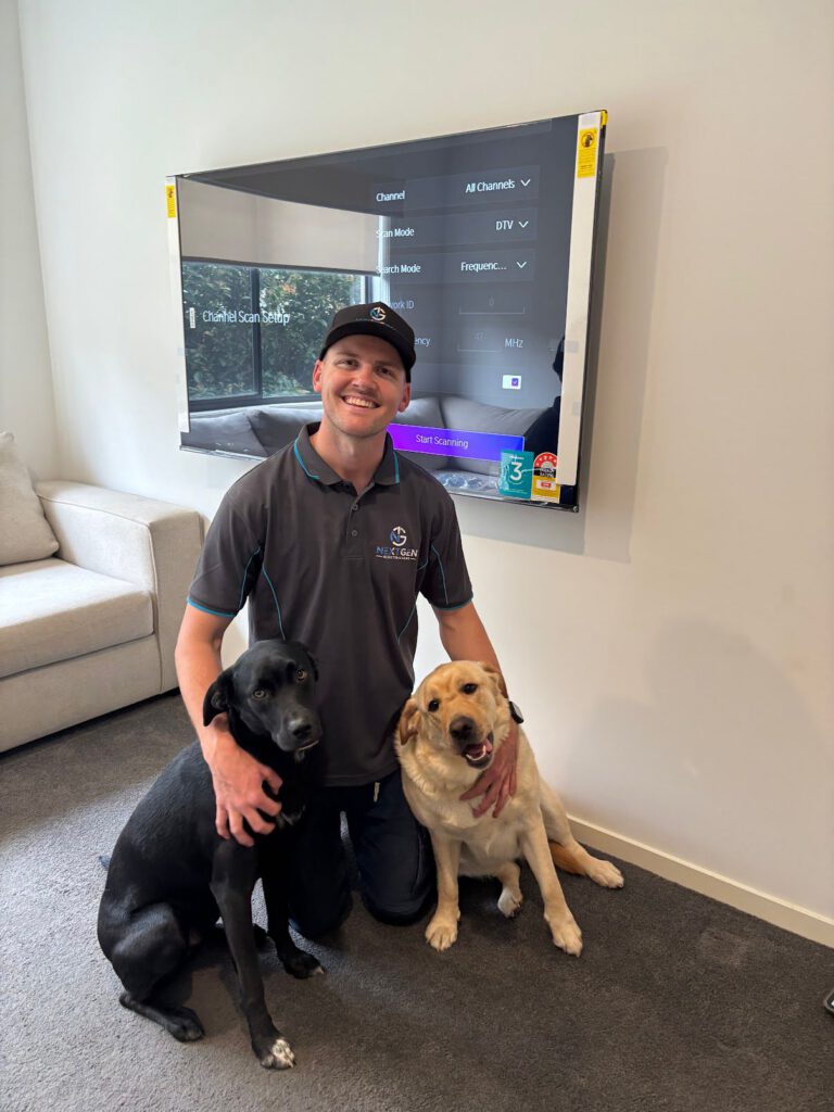 Harley kneeling with two of the client's dogs after a TV wall mount and tuning job