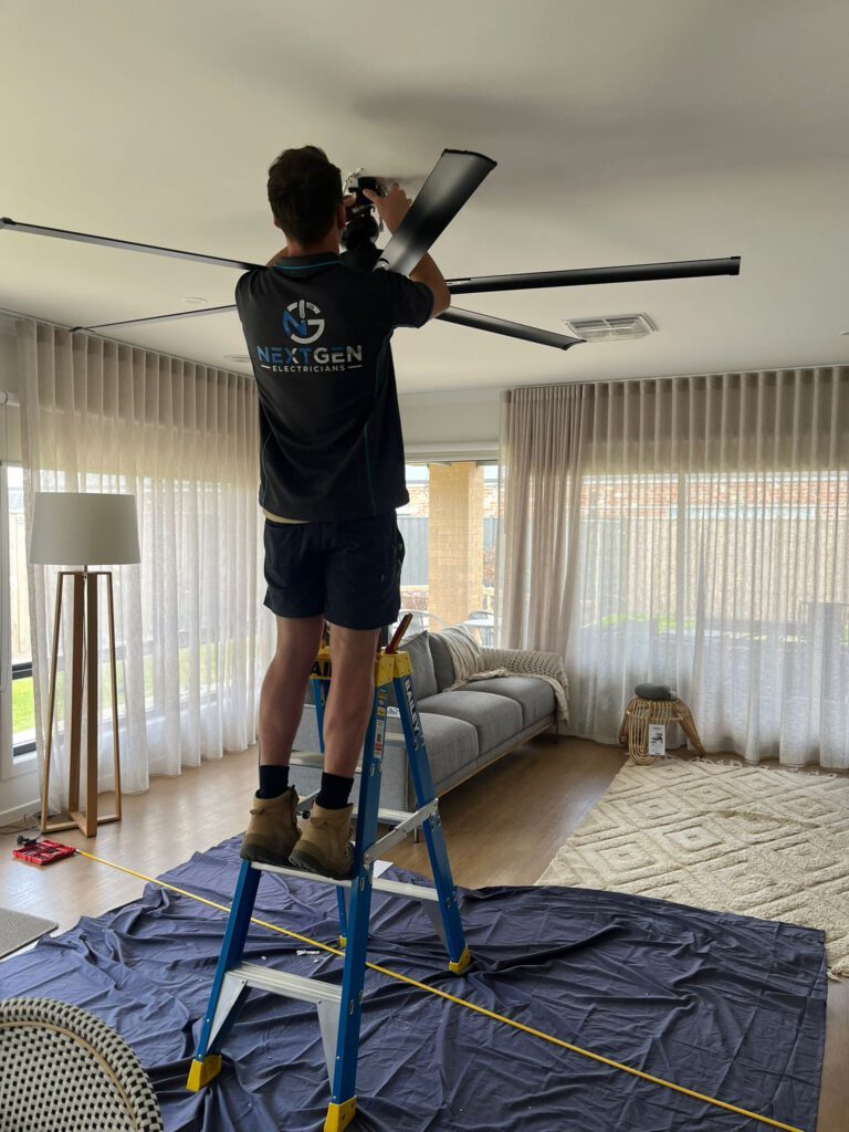 Harley installing a ceiling fan from a ladder