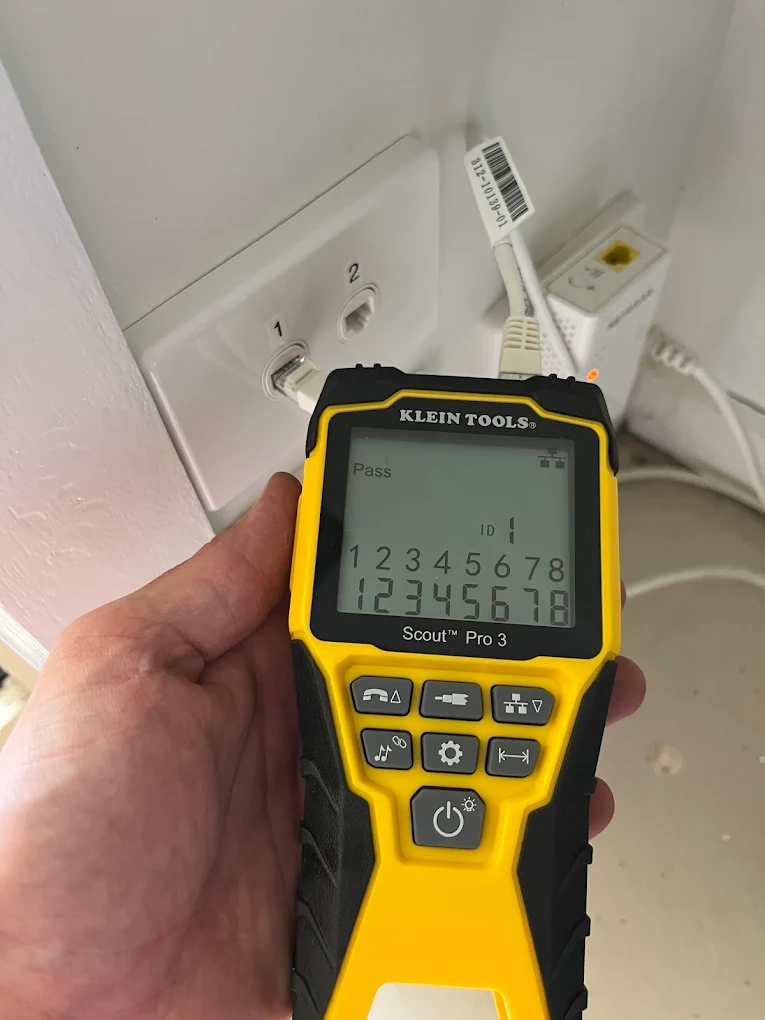 Klein Tools cable tester confirming a passing Cat6 connection at an NBN connection point in a home comms cupboard