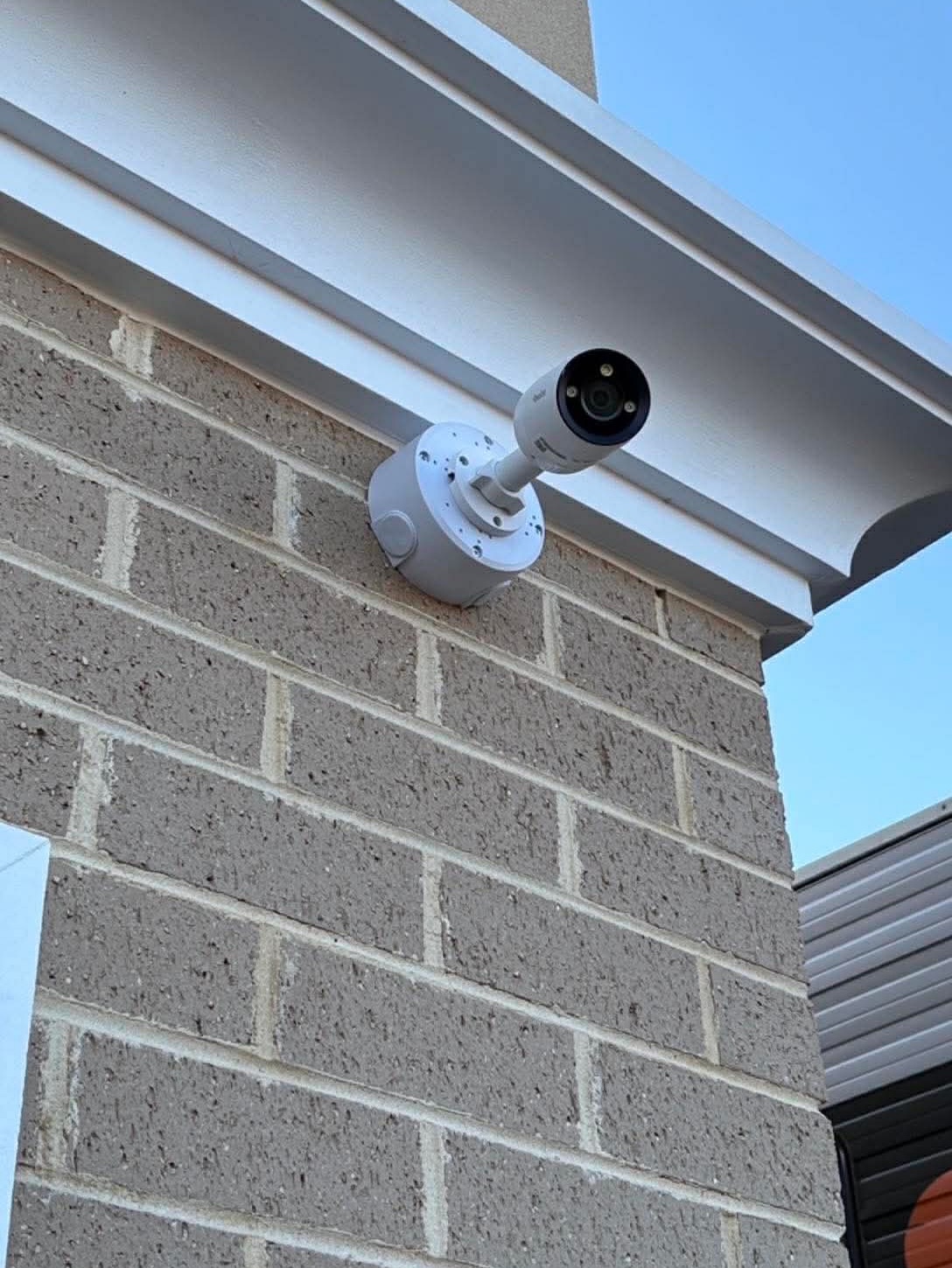 Dahua CCTV bullet camera mounted under eaves on a brick exterior