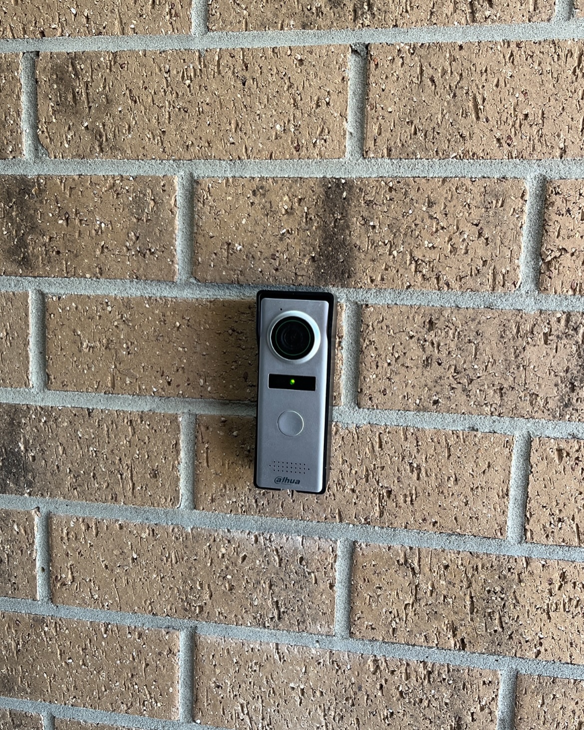 Dahua video doorbell intercom installed on a brick wall at the front entry