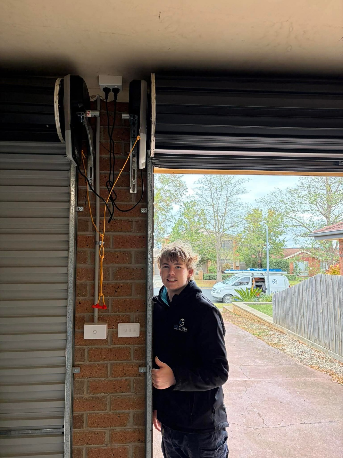 NextGen electrician at a garage doorway with roller door motors and power installed