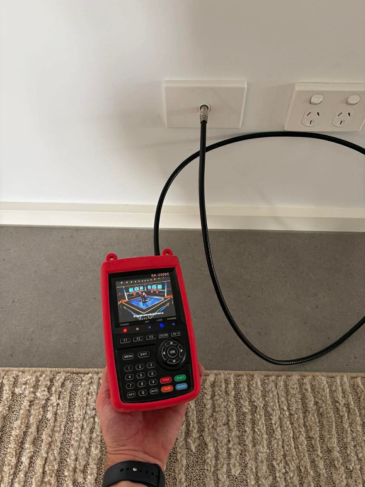 Satlink TV signal meter testing the coax connection at a wall mounted TV outlet
